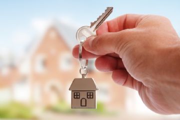 Chiavi in mano con portachiavi a forma di casa